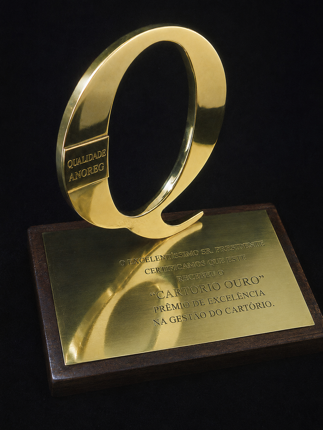 Escultura institucional em metal dourado com placa comemorativa